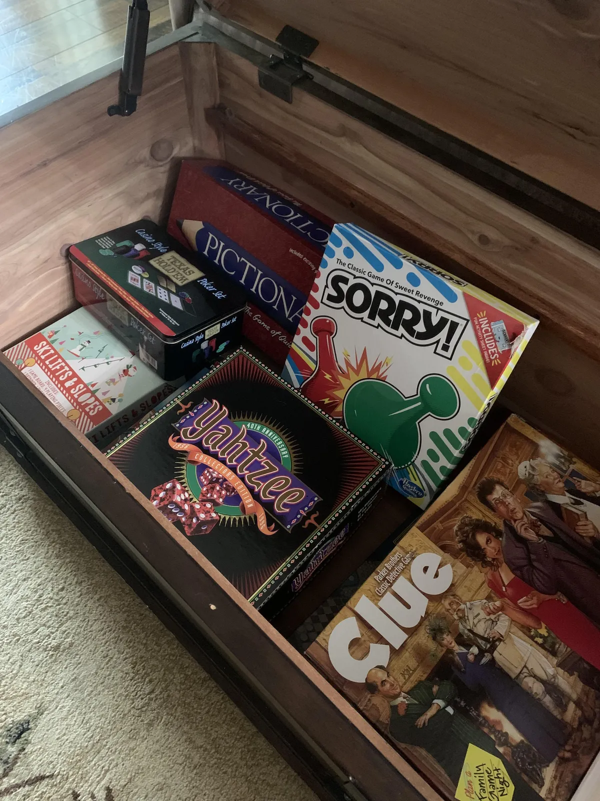 A playful scene with game boxes atop a wooden chest, a cozy rug underfoot, and an inviting area that suggests group activities like game nights or storytelling.